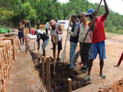 Les habitants du village malgache en train de construire la maison de l'eau. - Ambohimad