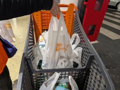 Une bénévole met un sac donné par un client dans un caddie avant d'être transporté jusqu'au camion. - Benjamin Deglave