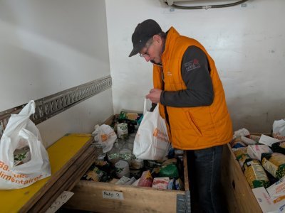 Jean, chauffeur bénévole de l'association, effectue un premier tri des dons dans les boîtes en bois de son camion. - Benjamin Deglave